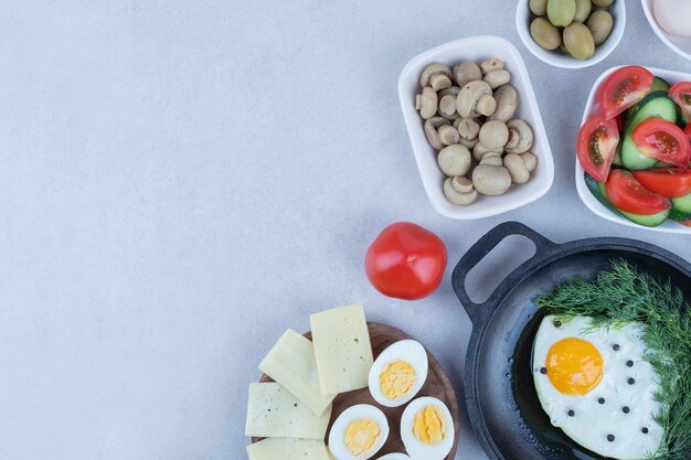 Sartén con tortilla y huevos duros, queso, tomate, champiñones.