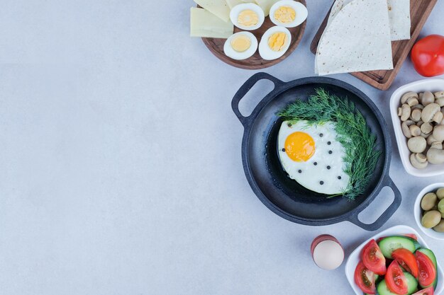 Sartén con tortilla y huevos duros, queso, tomate, champiñones.