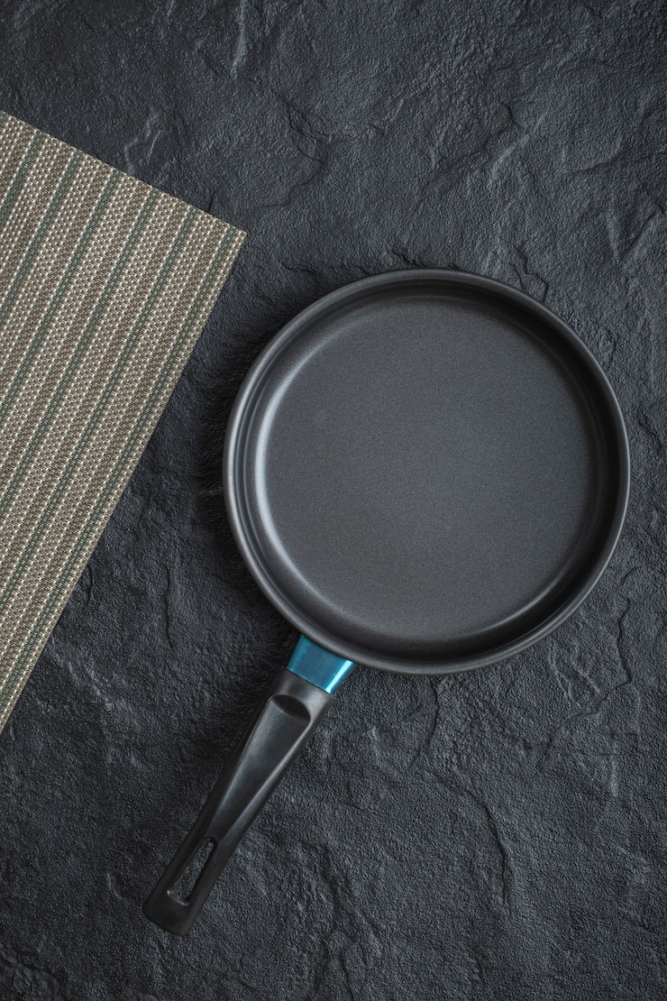 Foto gratuito sartén vacía para cocinar colocada sobre fondo negro
