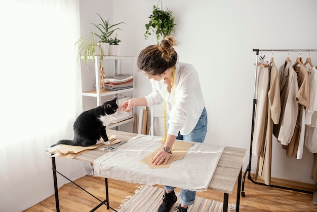 Sastre femenino trabajando en el estudio con gato