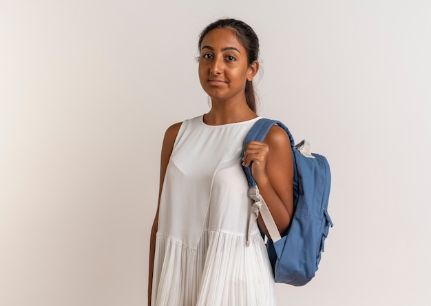 Satisfecho joven colegiala vistiendo bolsa trasera aislado en blanco