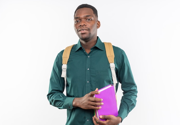 Satisfecho joven estudiante afroamericano con mochila sosteniendo libros