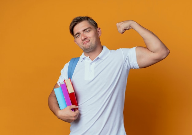 Satisfecho joven guapo estudiante vistiendo bolsa trasera sosteniendo libros