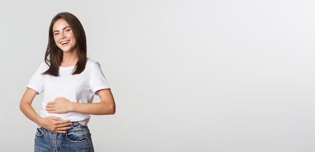 Foto gratuita satisfecho niña morena sonriente frotando el vientre después de comer comida deliciosa