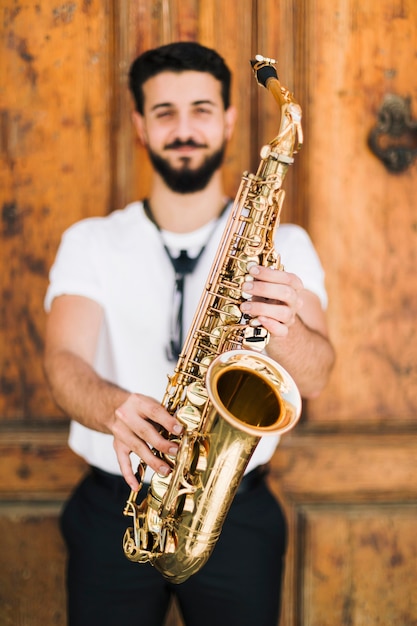 Saxofón sostenido por el músico sonriente defocused