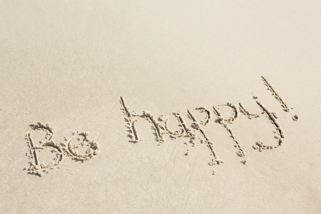 Sé feliz por escrito en la arena