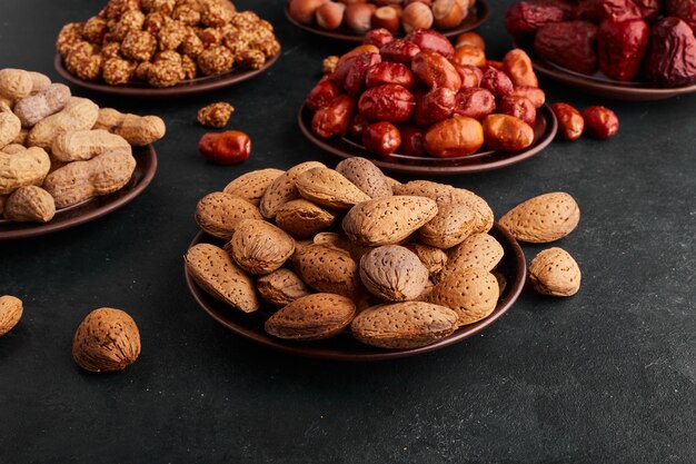 Secar dátiles y almendras en platillo en espacio negro.