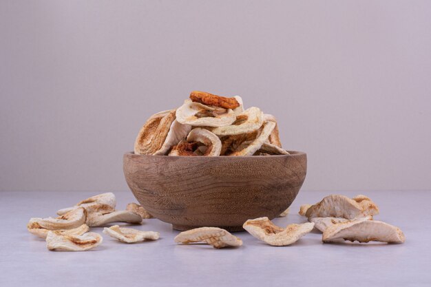 Secar las rodajas de manzana en una taza de madera sobre una superficie gris