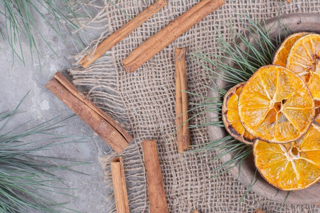 Secar rodajas de naranja en una taza con ramas de roble y canela