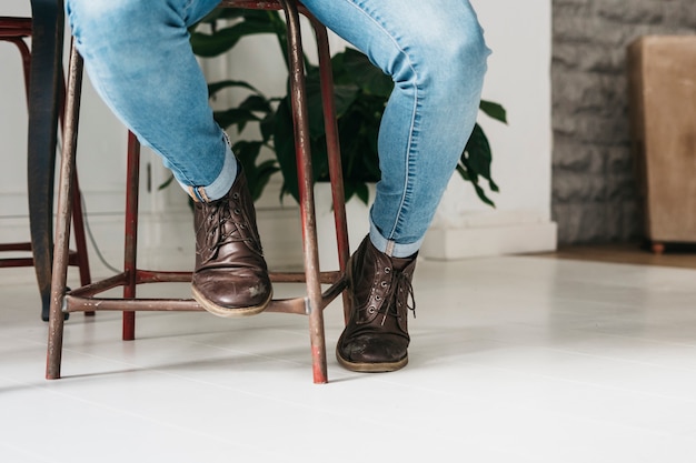 Sección baja de elegante hombre elegante en zapatos marrones sentado en taburete