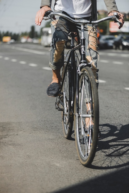 Sección baja del hombre montando bicicleta en la carretera