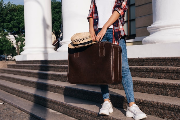 Sección baja de mujer con bolsa de equipaje de pie en la escalera al aire libre