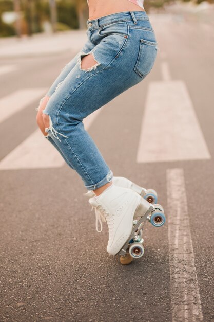 Sección baja de una mujer vestida con un patín blanco en equilibrio