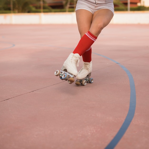 Sección baja de una patinadora femenina patinando en la cancha