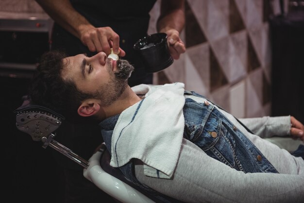 Sección intermedia de barbero aplicando crema en la barba de los clientes