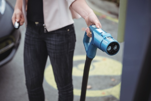 Foto gratuita sección intermedia de mujer cargando coche eléctrico