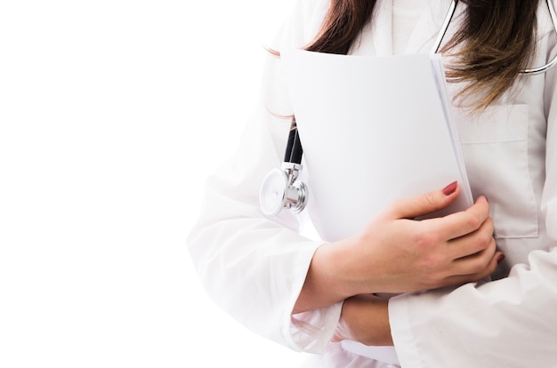 Sección media de una doctora con estetoscopio alrededor de su cuello con informe médico en la mano