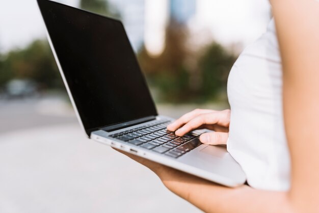 Sección media de empresaria usando laptop sosteniendo en la mano