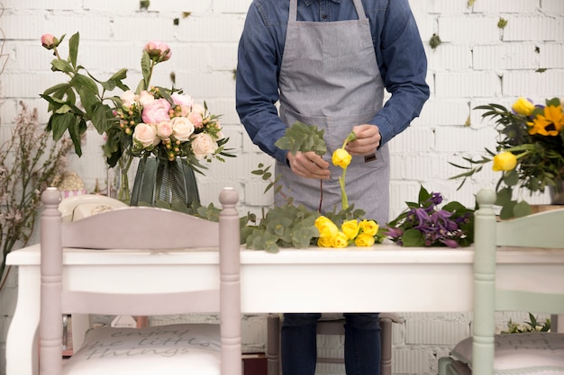 Sección media del hombre arreglando las flores sobre la mesa