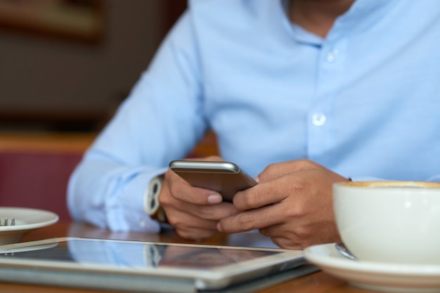 Sección media del hombre leyendo noticias en línea tomando un café