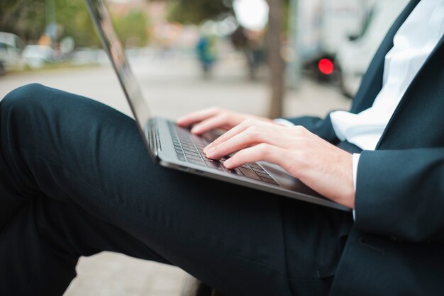 Sección media de un hombre de negocios escribiendo en la computadora portátil