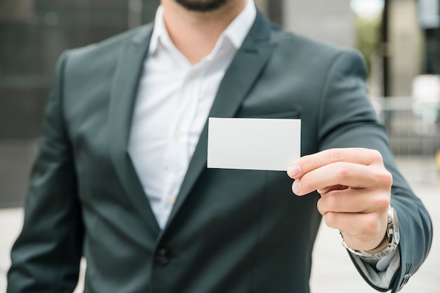 Sección media de un hombre de negocios que muestra la tarjeta en blanco blanca