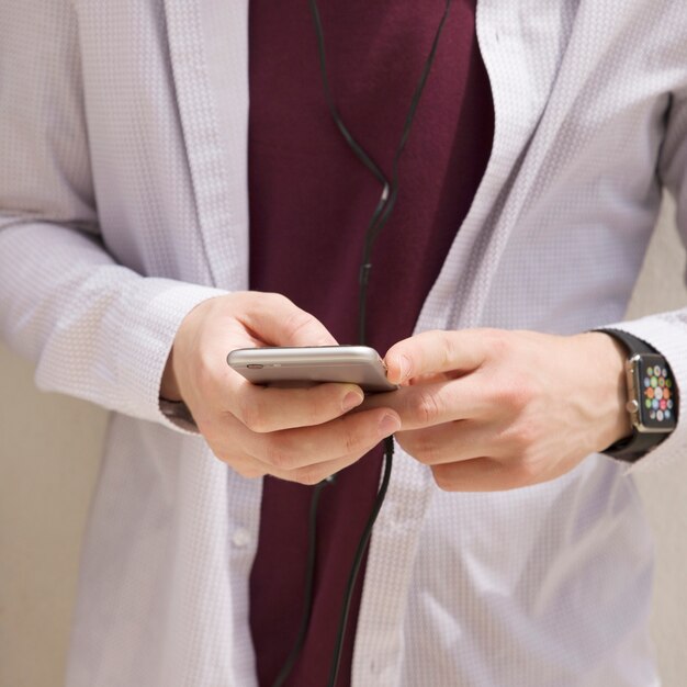 Sección media de un hombre que sostiene el teléfono móvil a disposición