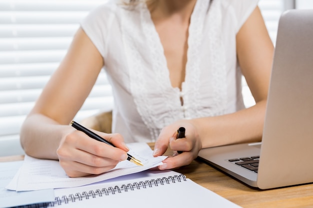 La sección media de una mujer escribiendo en un papel