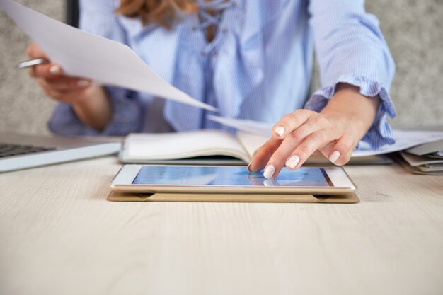 Sección media de mujer irreconocible que trabaja con tablet PC en el escritorio de la oficina