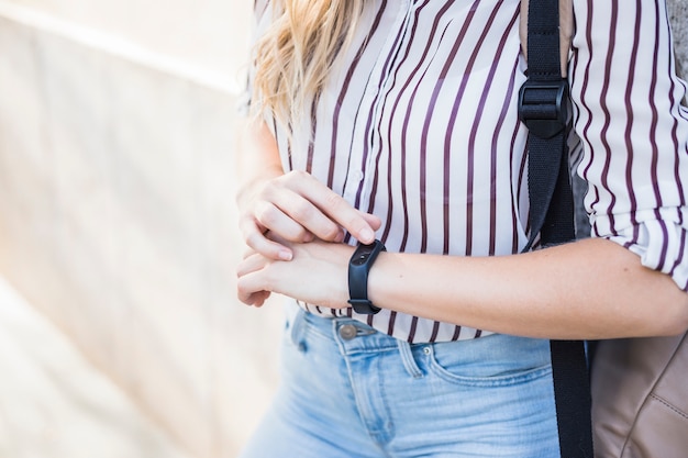 Sección media de la mujer joven que controla tiempo en el reloj digital