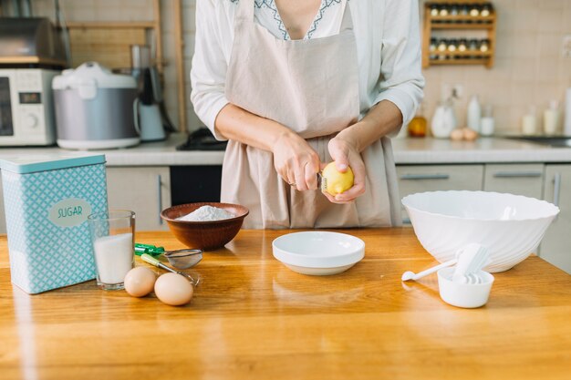 Sección media de una mujer rallando limón mientras preparaba pastel