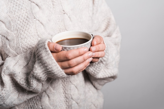 Sección media de mujer en ropa de lana con taza de café