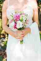 Foto gratuita sección media de una novia en vestido blanco con ramo de flores en sus manos