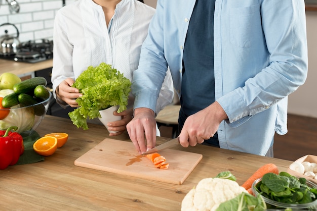 Foto gratuita sección media de pareja preparando la comida en el mostrador de la cocina