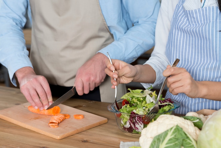 Foto gratuito sección media de pareja preparando la comida en el mostrador de la cocina