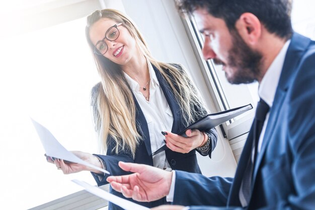 Secretaria de sexo femenino sonriente que muestra el documento al encargado masculino