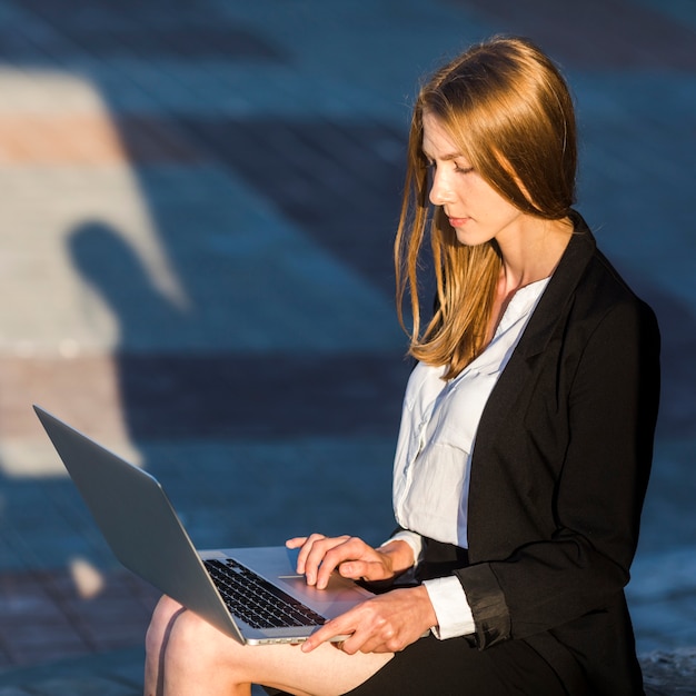 Foto gratuita secretaria usando su laptop al aire libre