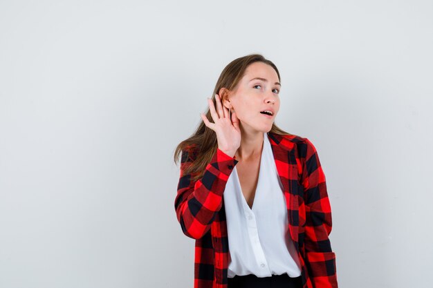 Secreto de escucha femenina hermosa joven en traje casual y mirando enfocado. vista frontal.