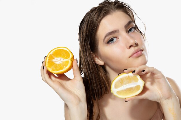 Secretos de la juventud. Cerca de la hermosa joven con rodajas de limón y naranja sobre blanco.