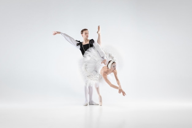 Secundario. Bailarines de ballet clásico agraciado bailando aislado sobre fondo blanco de estudio. Pareja en ropa tierna como personajes de cisne blanco. El concepto de gracia, artista, movimiento, acción y movimiento.