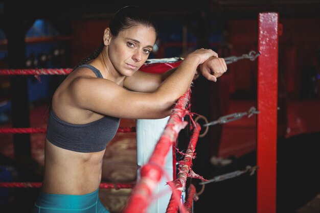 Segura boxeadora apoyándose en el ring de boxeo