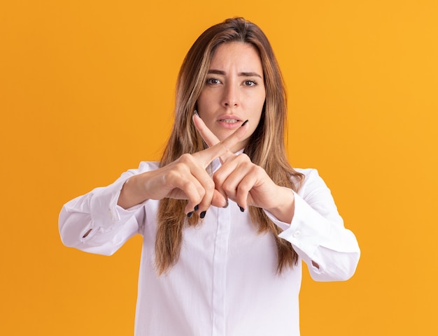 Segura joven bastante caucásica cruza los dedos sin gesticular ningún signo en naranja