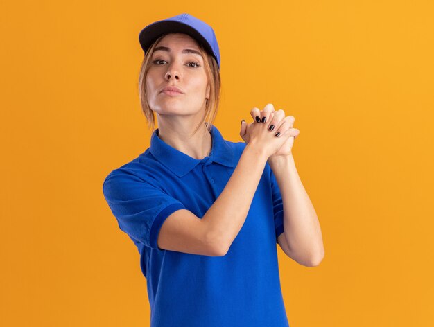 Segura joven bonita entrega mujer en uniforme tiene las manos juntas aisladas