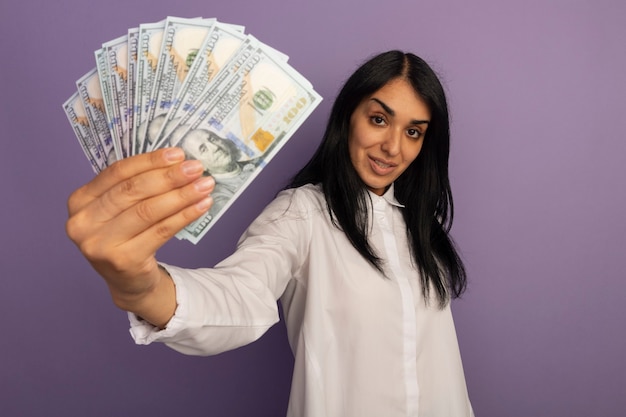 Segura joven hermosa mujer vestida con camiseta blanca sosteniendo dinero en efectivo