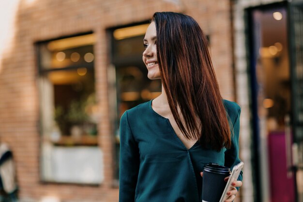 Segura mujer europea en vestido oscuro mirando en la distancia