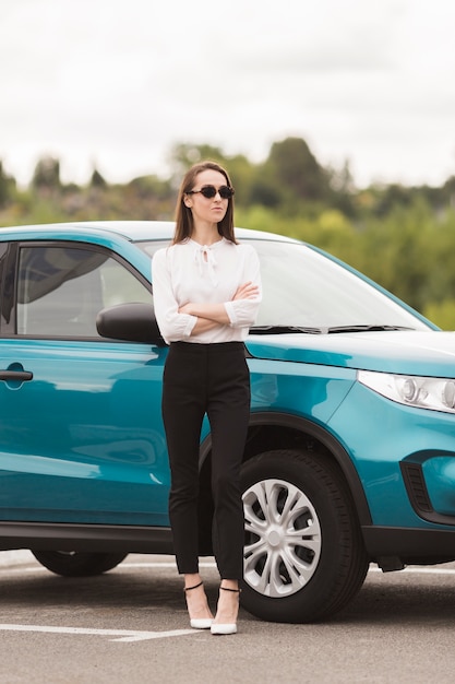 Segura mujer posando delante de un coche