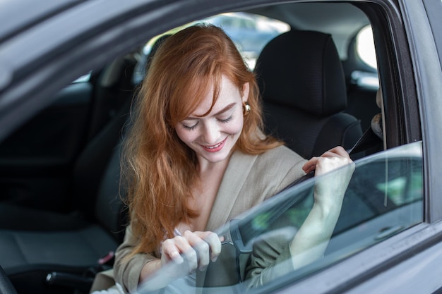 La seguridad es lo primero Hermosa dama caucásica abrochándose el cinturón de seguridad del coche Bastante joven conduciendo su nuevo coche Bastante joven conduciendo su nuevo coche Mujer abrochándose el cinturón de seguridad en el coche