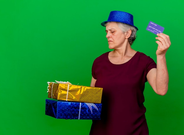 Seguro de anciana con sombrero de fiesta tiene cajas de regalo y tarjeta de crédito en verde