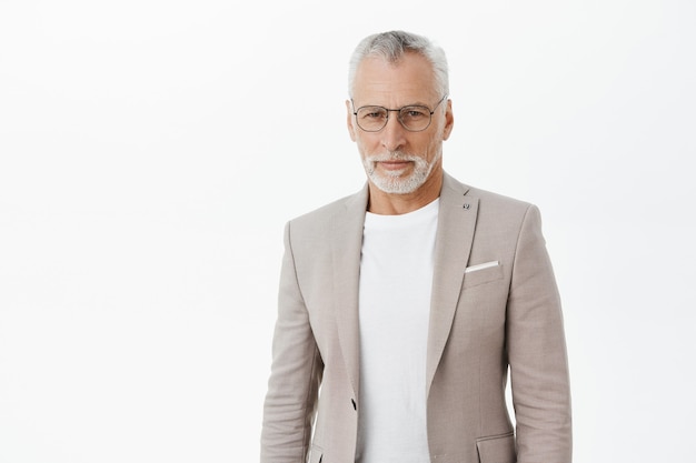 Seguro apuesto hombre de negocios en traje y gafas mirando serio