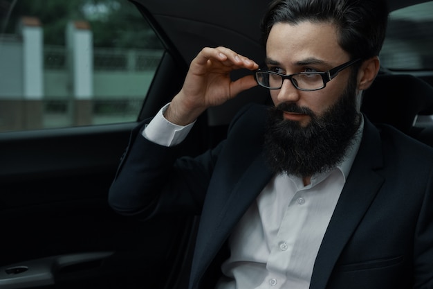 Seguro empresario sentado en el asiento trasero del coche